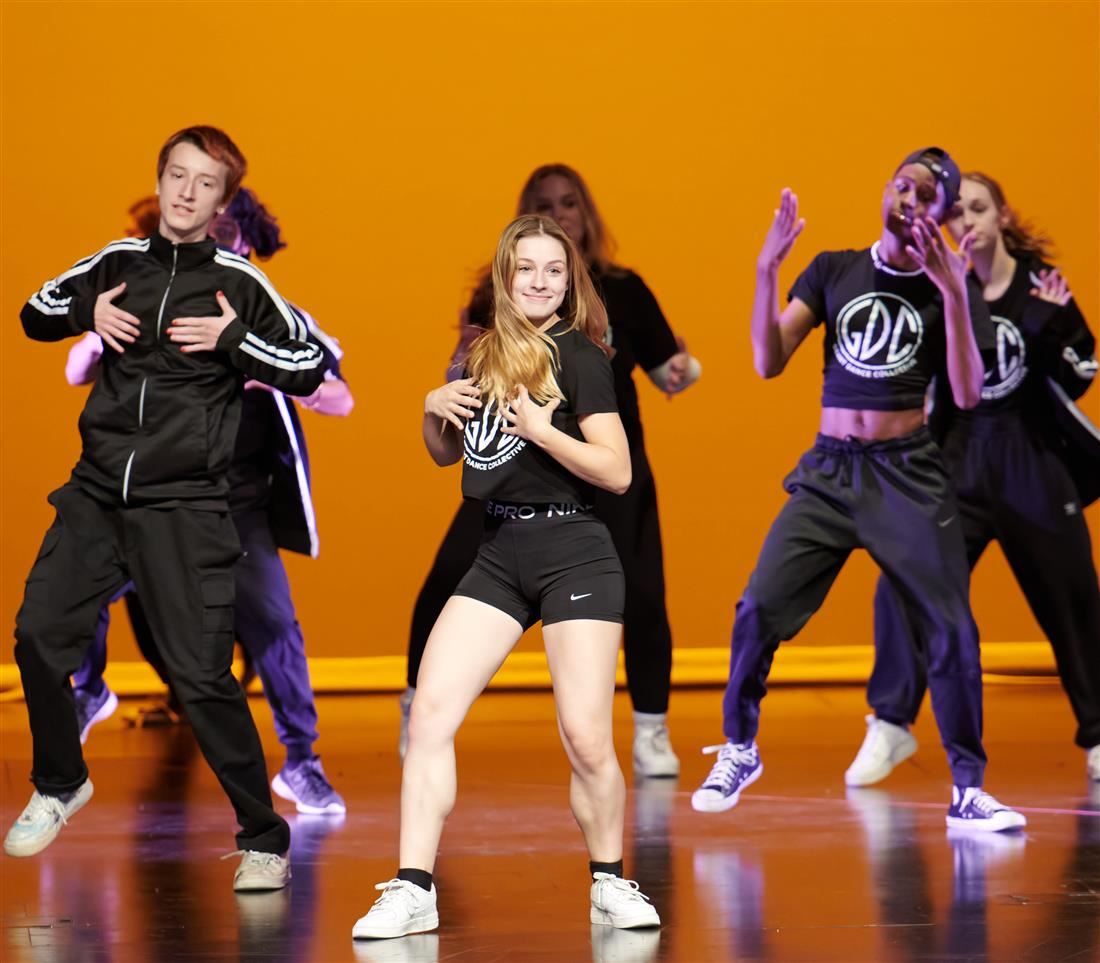 Student dancers dancing behind yellow background